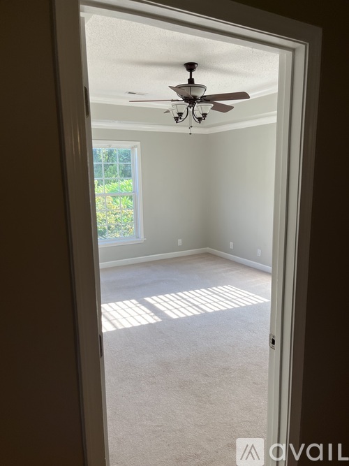 A room with a ceiling fan and a door leading to a garden.