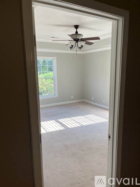 A room with a ceiling fan and a door leading to a garden.