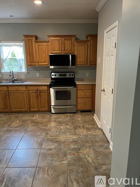A kitchen with wooden cabinets and a tiled floor.