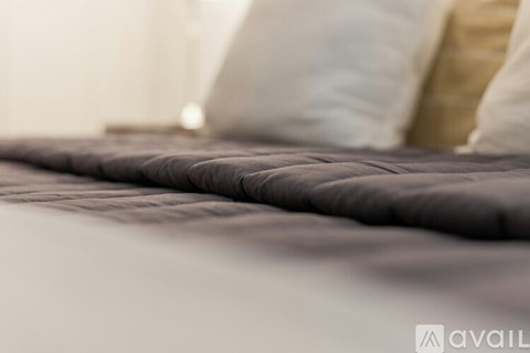 A close up of a bed with a grey comforter.