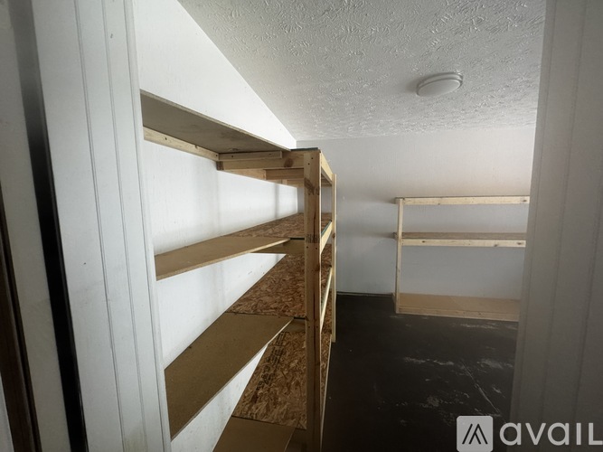 A room with a white ceiling and a wall with a window, and a shelf with a brown material.