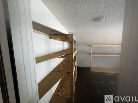 A room with a white ceiling and a wall with a window, and a shelf with a brown material.