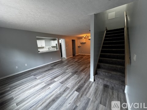 A spacious room with a staircase leading to another floor.