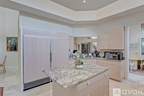 A kitchen with a marble countertop and a refrigerator with a frosted glass door.