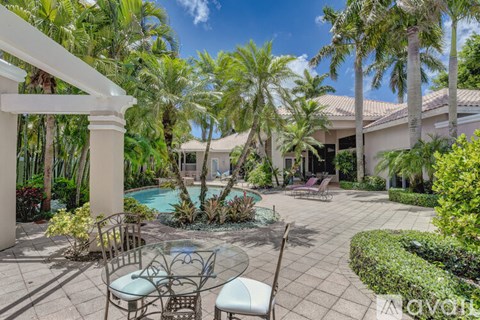 A patio with a table and chairs overlooks a pool.