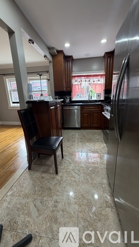 A kitchen with a refrigerator, sink, and a chair.