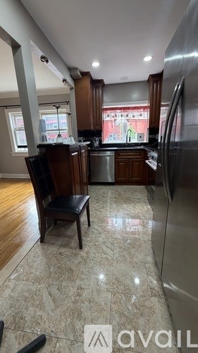 A kitchen with a refrigerator, sink, and a chair.