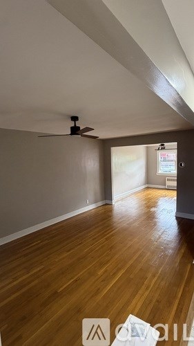 A room with a ceiling fan and wooden flooring.