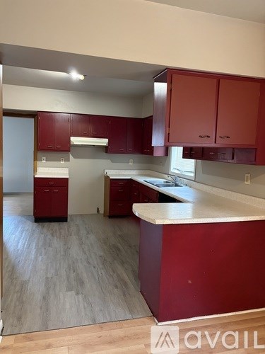 A kitchen with red cabinets and a white counter.