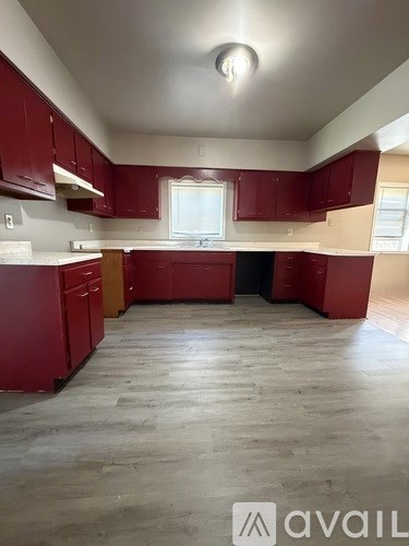 A kitchen with red cabinets and a window.