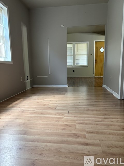 A room with wooden flooring and a door on the right.