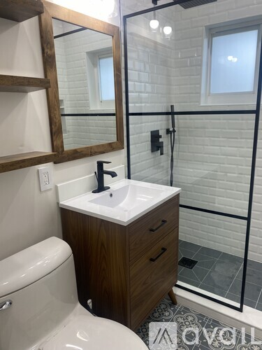 A bathroom with a toilet, sink, mirror, and shower.