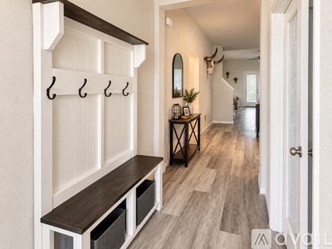 A hallway with a bench and coat hooks.