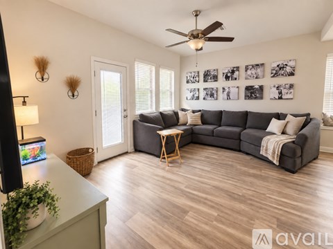 A living room with a grey sofa, a wooden coffee table, and a ceiling fan.