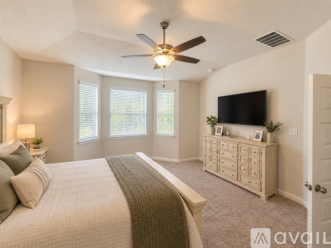 A bedroom with a large bed and a television on the wall.