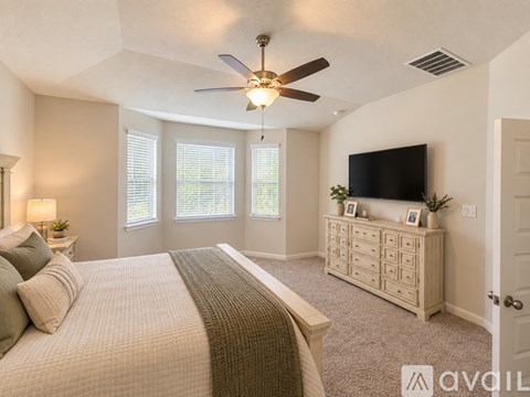 A bedroom with a large bed and a television on the wall.