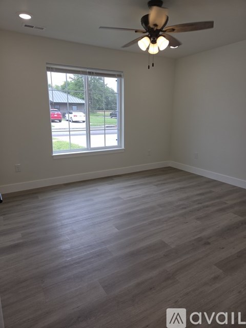 A room with a ceiling fan and a large window.