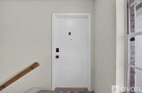 A white door with a black handle and a small black letter "D" on the top left corner.