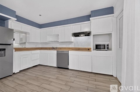 A kitchen with white cabinets and a wooden countertop.