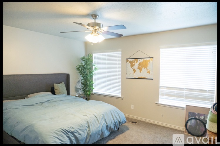 A bedroom with a bed, a ceiling fan, and a world map on the wall.