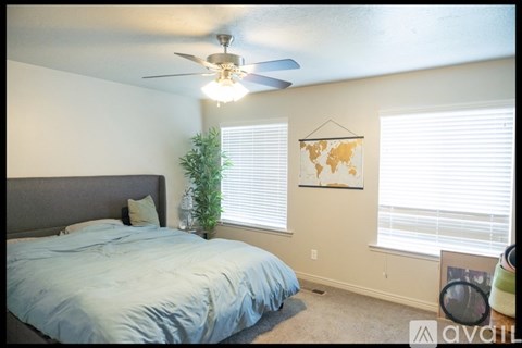 A bedroom with a bed, a ceiling fan, and a world map on the wall.