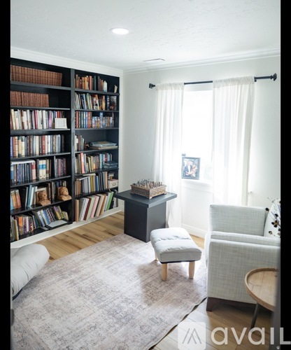 A living room with a bookshelf filled with books and a chair.