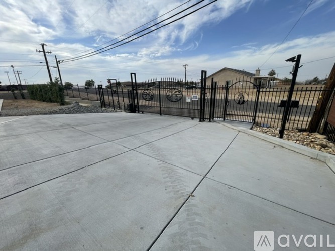 A concrete area with a black fence and a building in the background.