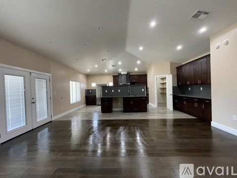 A spacious kitchen and living room with dark wood floors and white walls.