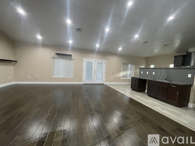 A spacious room with wooden flooring and a bar area.