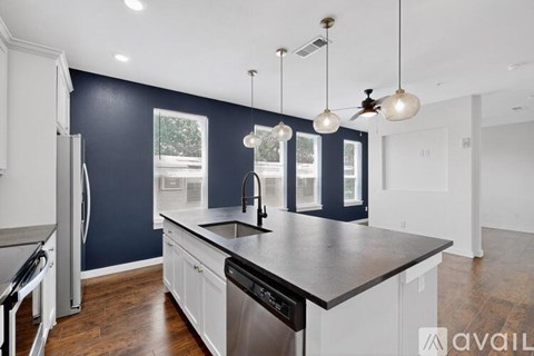A kitchen with dark blue walls and white cabinets.