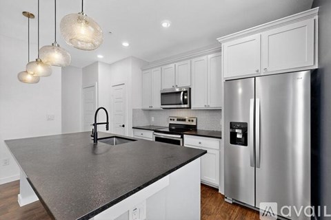 A modern kitchen with a stainless steel refrigerator and a granite countertop.