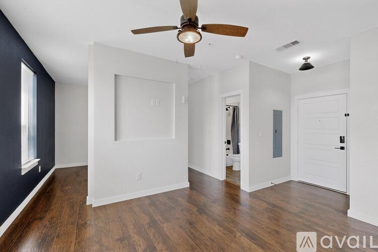 A spacious room with a ceiling fan and wooden flooring.