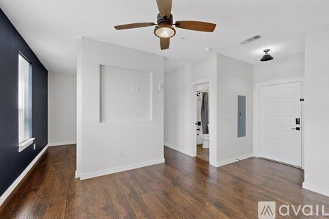 A spacious room with a ceiling fan and wooden flooring.