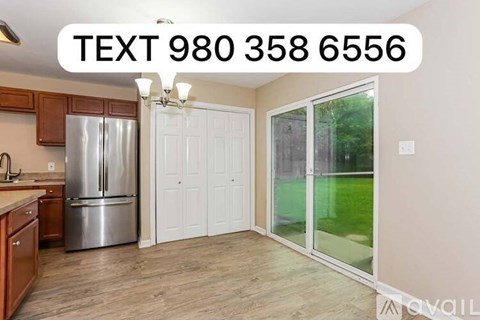 A kitchen with a refrigerator, cabinets, and a countertop with a text box on the wall.