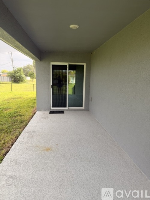 A concrete covered walkway leads to a glass door.