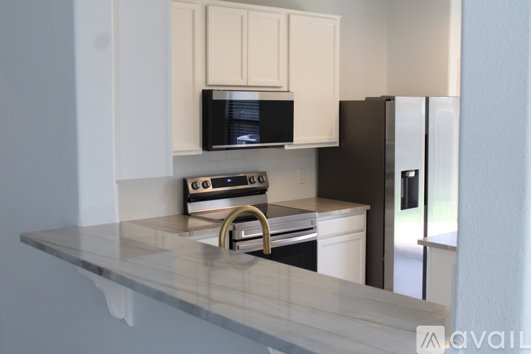 A kitchen with a black fridge and a microwave above the stove.