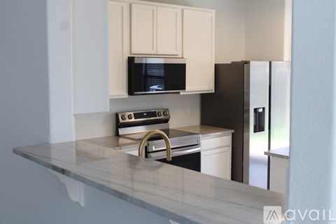 A kitchen with a black fridge and a microwave above the stove.