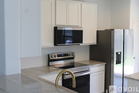 A kitchen with a black fridge and a black microwave.