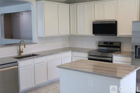 A kitchen with white cabinets and a black microwave above the stove.
