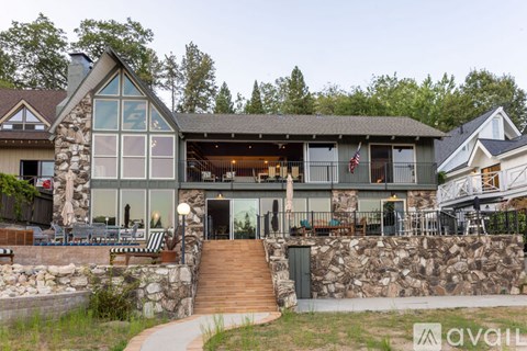 A house with a stone wall and a wooden staircase leading to the entrance.