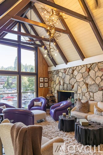 A living room with a stone fireplace and purple chairs.