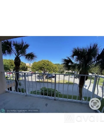 A balcony with a metal railing and palm trees in the background.