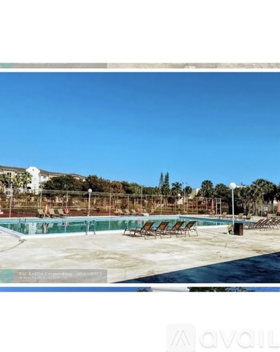A pool area with chairs and a clear blue sky.