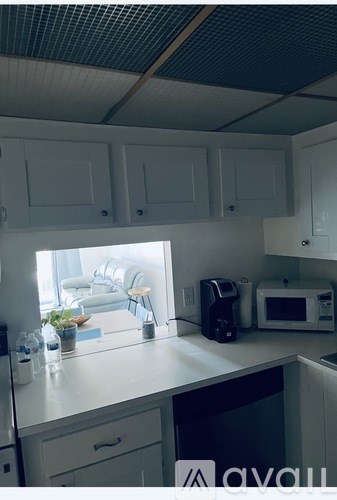 A kitchen with white cabinets and a black counter.