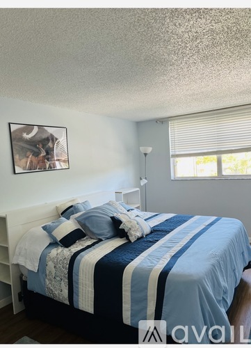 A bedroom with a bed covered in a blue and white striped comforter.