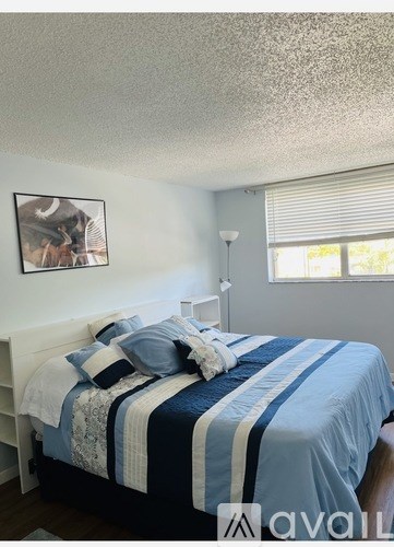 A bedroom with a bed covered in a blue and white striped comforter.