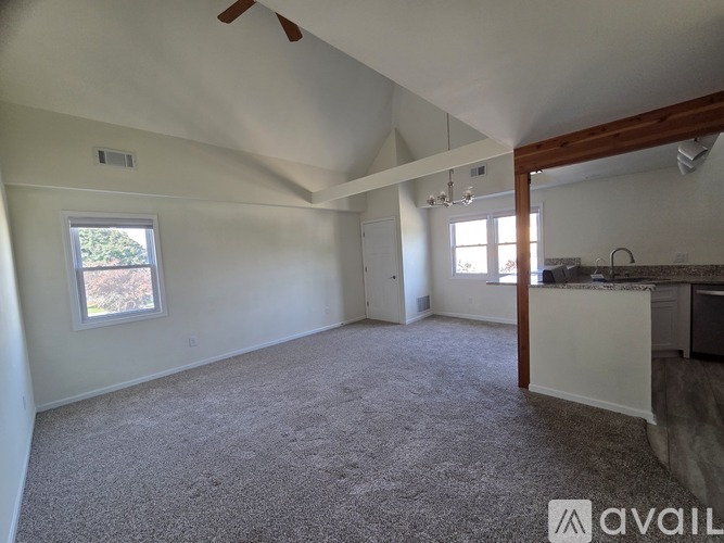A spacious room with a carpeted floor and a ceiling fan.