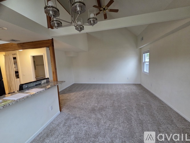 A spacious room with a ceiling fan and carpeted floor.