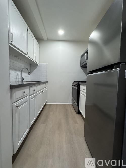 A kitchen with white cabinets and a black refrigerator.