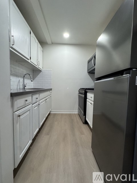 A kitchen with white cabinets and a black refrigerator.
